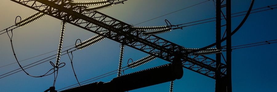 Close-up silhouette of a part of heavy-duty industrial pylon for electricity distribution with ceramic insulators and surge arresters. Blackout power energy and electricity infrastructure concept.